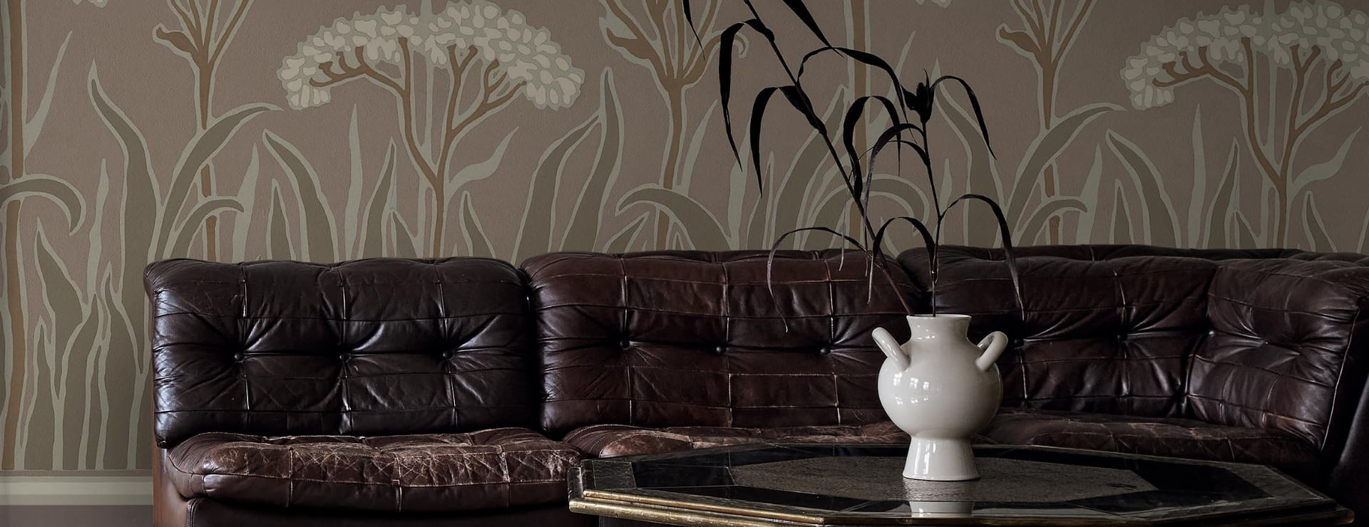 Bilde av stue med sofa foran vegg med tapet