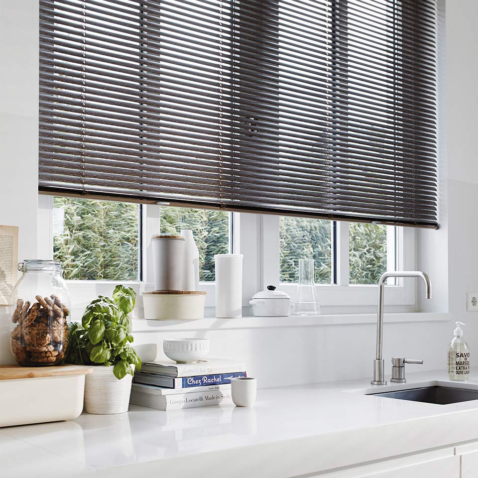 Lyst kjøkken med mørk persienne foran stort kjøkkenvindu