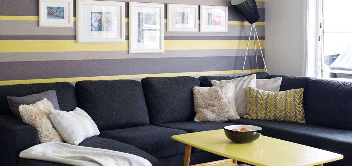 Mørk, stor sofa og lime-gult bord i stue