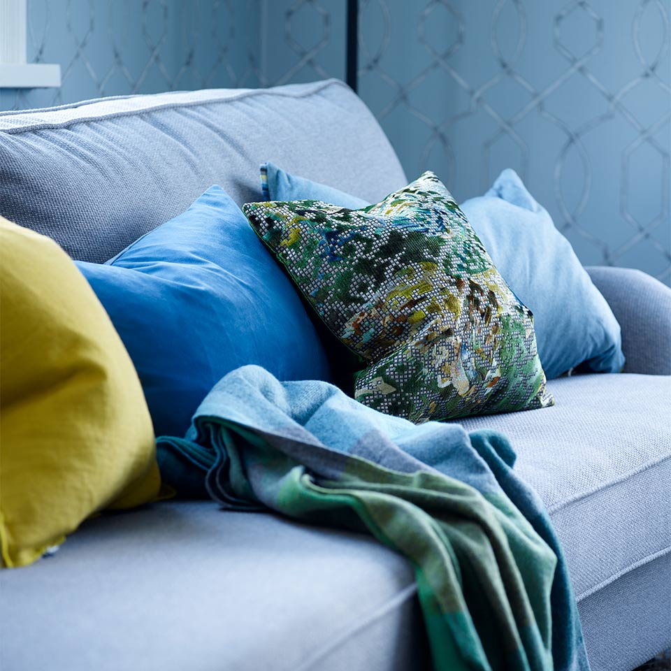 Blå sofa med blå, gule og mønstrete puter.