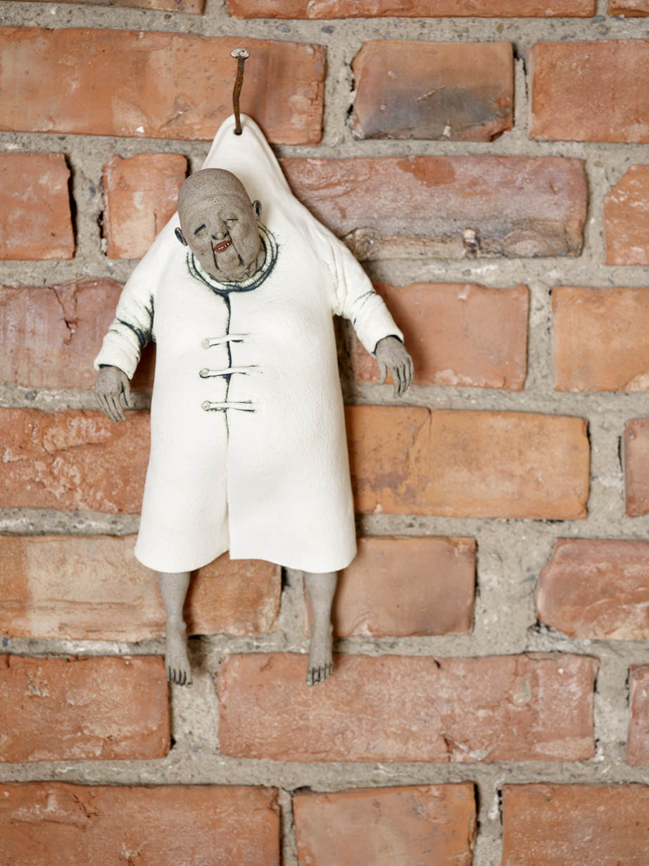 Figur hengende på murvegg.