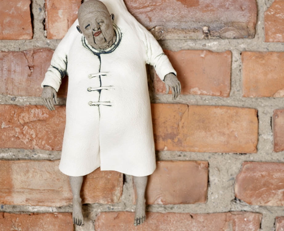 Figur hengende på murvegg.