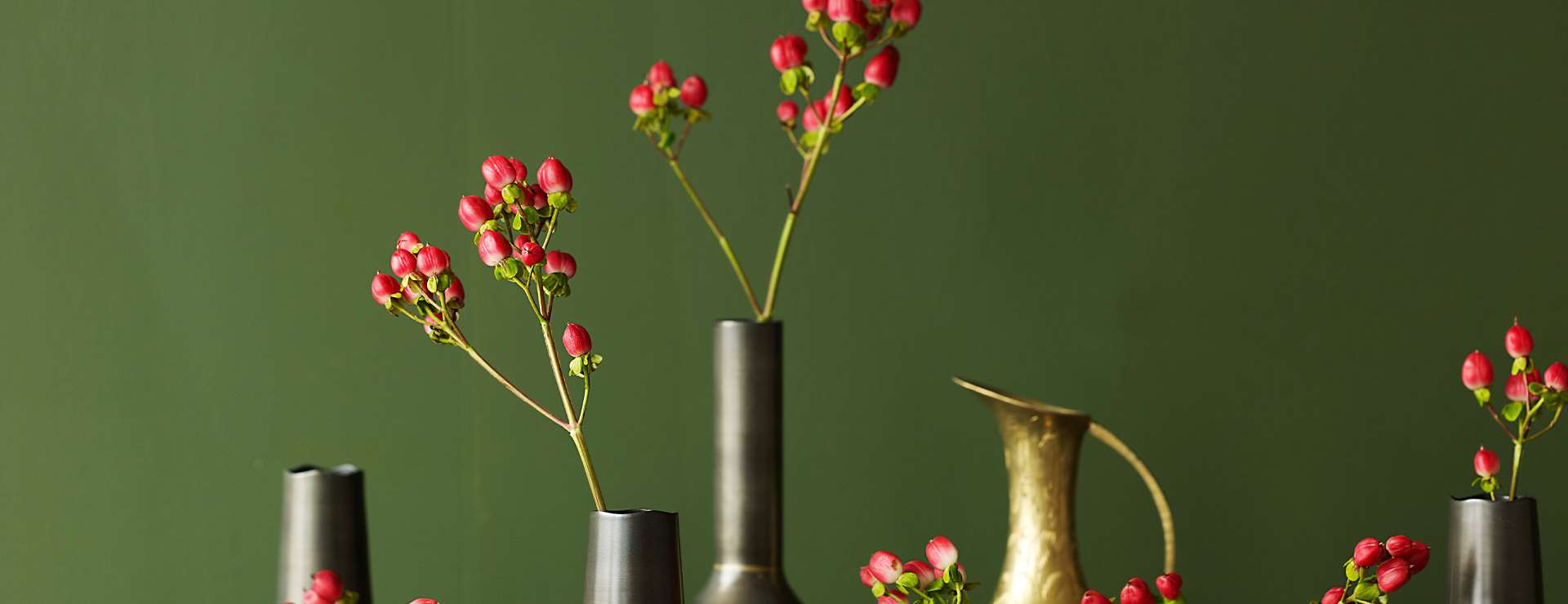 Vaser med røde blomster foran en vegg i årets farge 2012 - grønn
