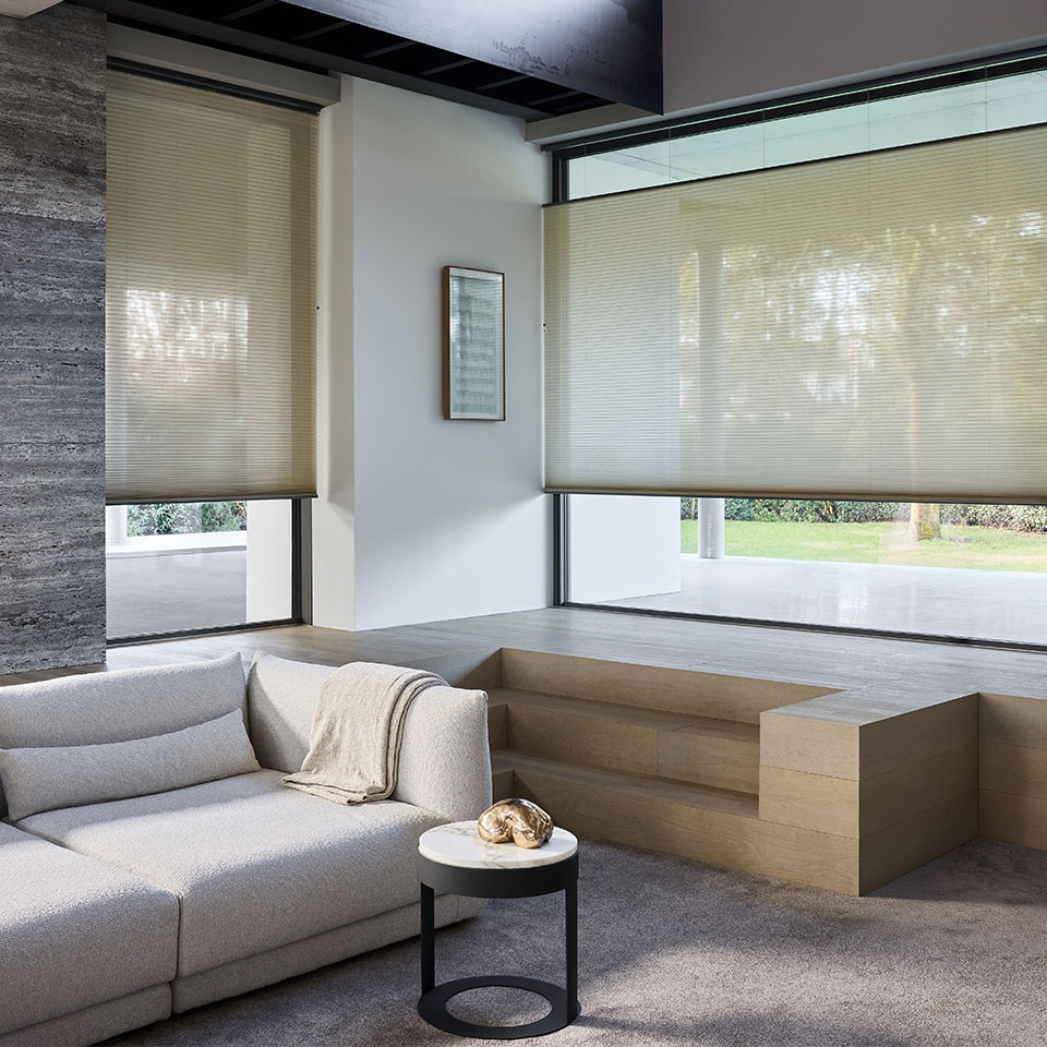 Lys stue med naturfarget Duette plisségardin foran store vindusflater