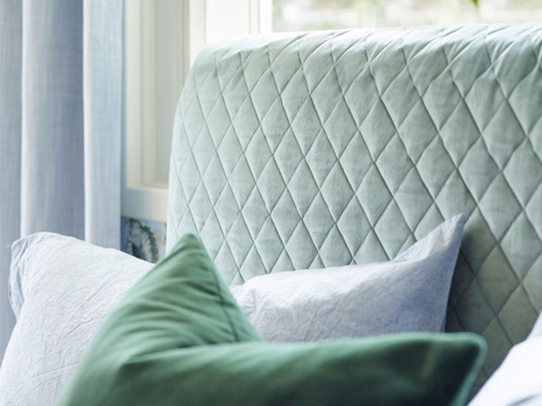 Sengegavl i grønt stoff.