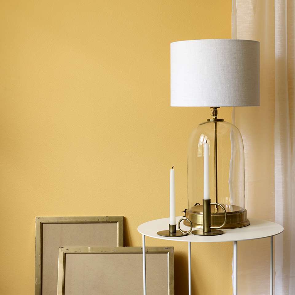Hvit lampe foran varm gul vegg.