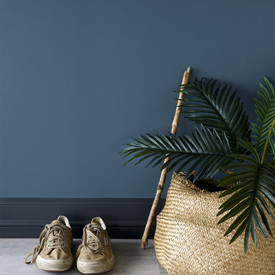 Et par sko og en kurv foran mørkeblå vegg.
