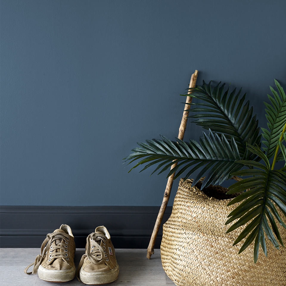 Et par sko og en kurv foran mørkeblå vegg.