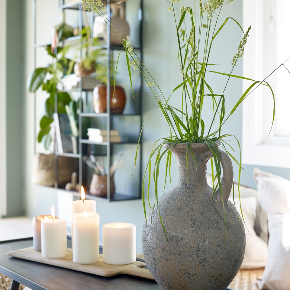 BLomster i vase foran vegg med fargen grønt glass