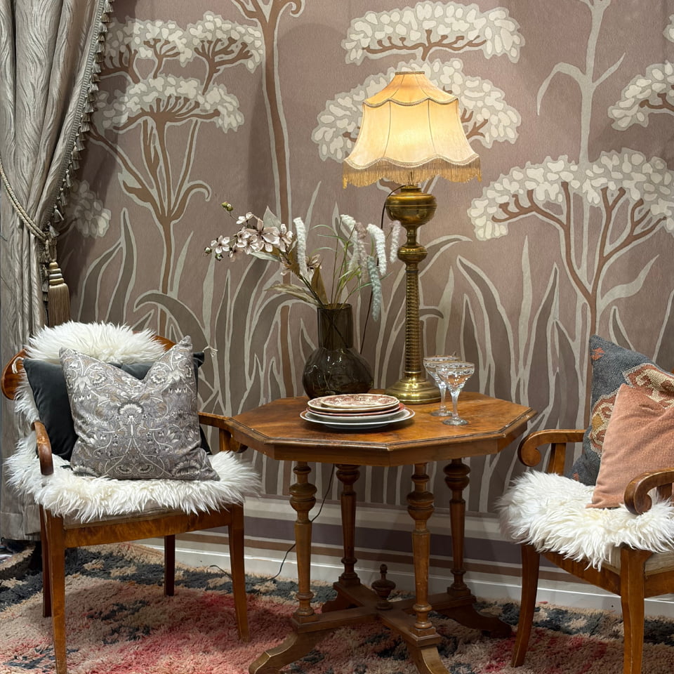 Bilde av tapet med blomster og utstilling med stol og bord og tapet bak.
