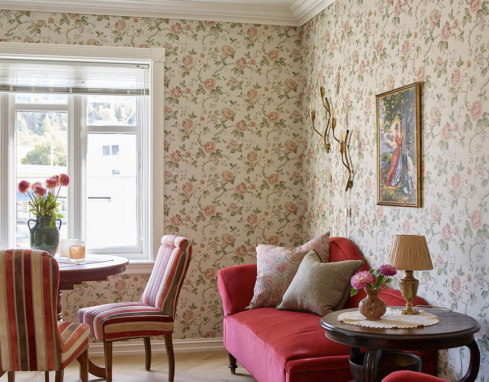 Røde møbler og blomster tapet.