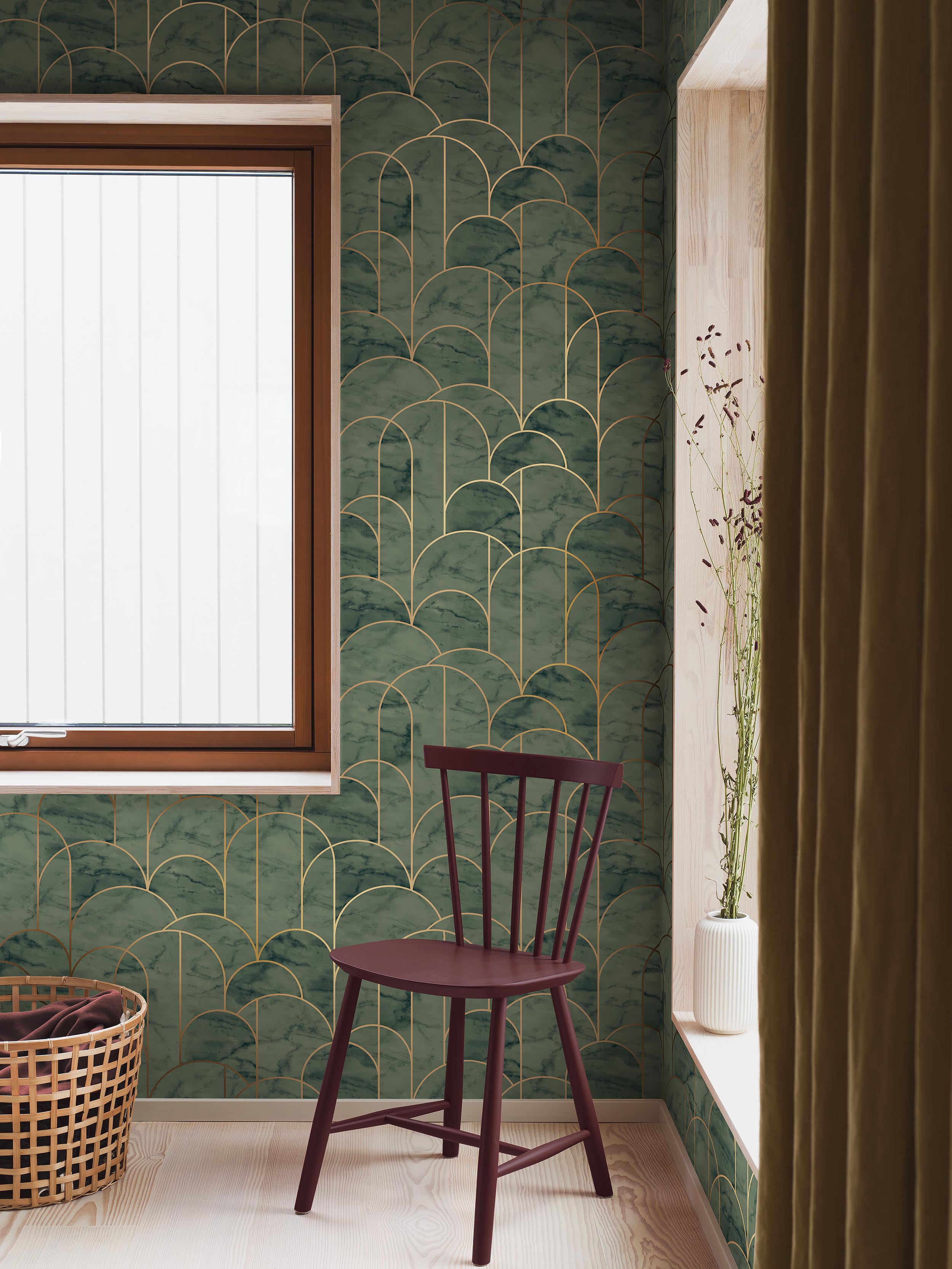 Vindukrok med grønn art deco-tapet i mønster av buer, en burgunder pinnestol, flettet kurv og en vase med tørkede blomster ved vinduet.