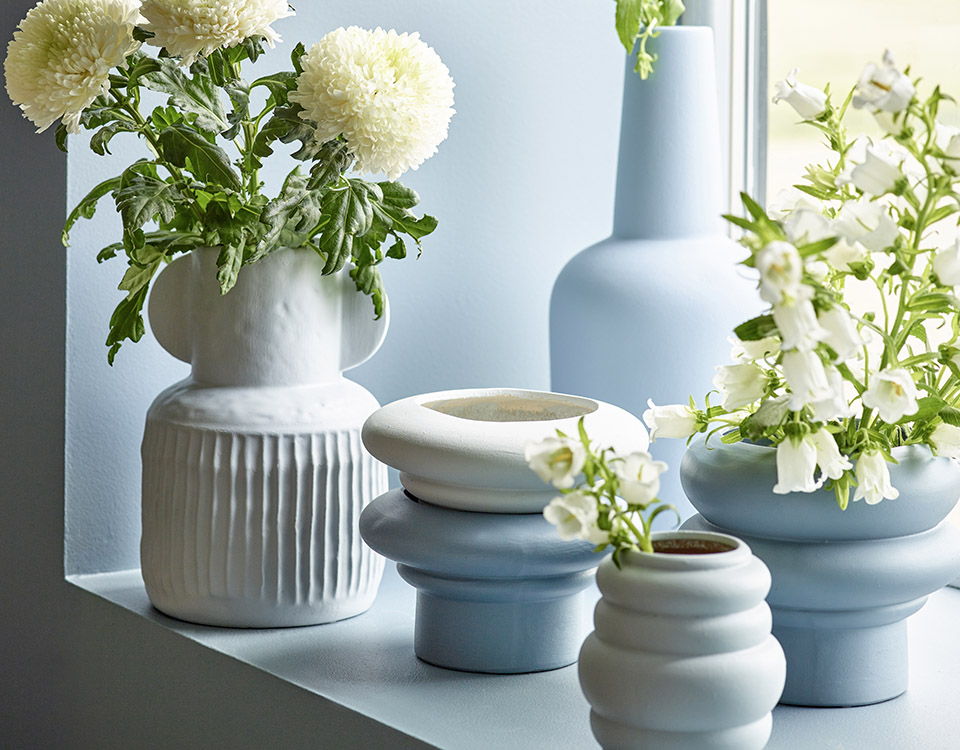 Dempet blå i vinduskarm sammen med vaser og blomster