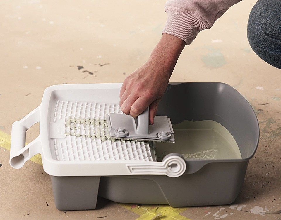 Hånd som dypper Rolling Pad forsiktig i malingsbrettet