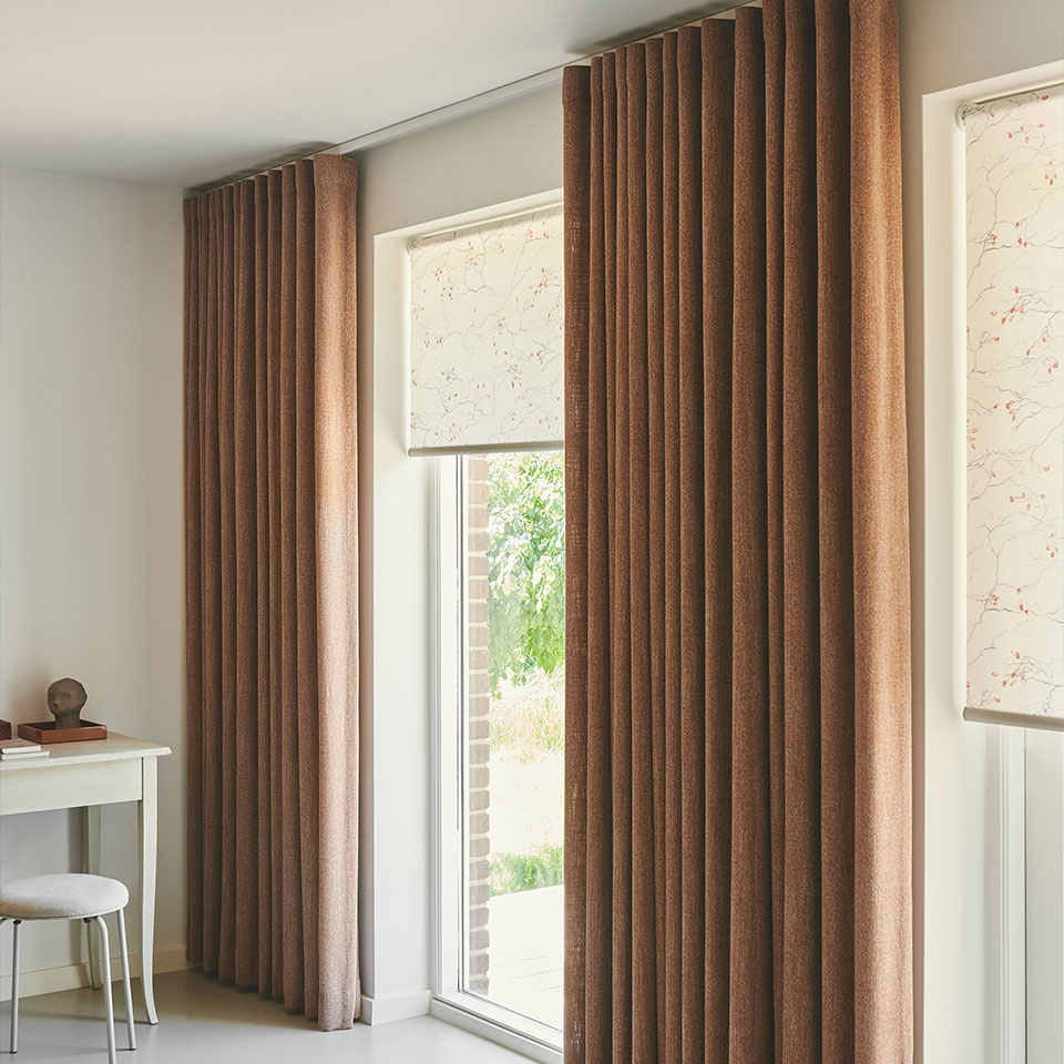 Rullegardin med diskret mønster foran store vindusflater, og dekor-gardiner i matchende fargetoner